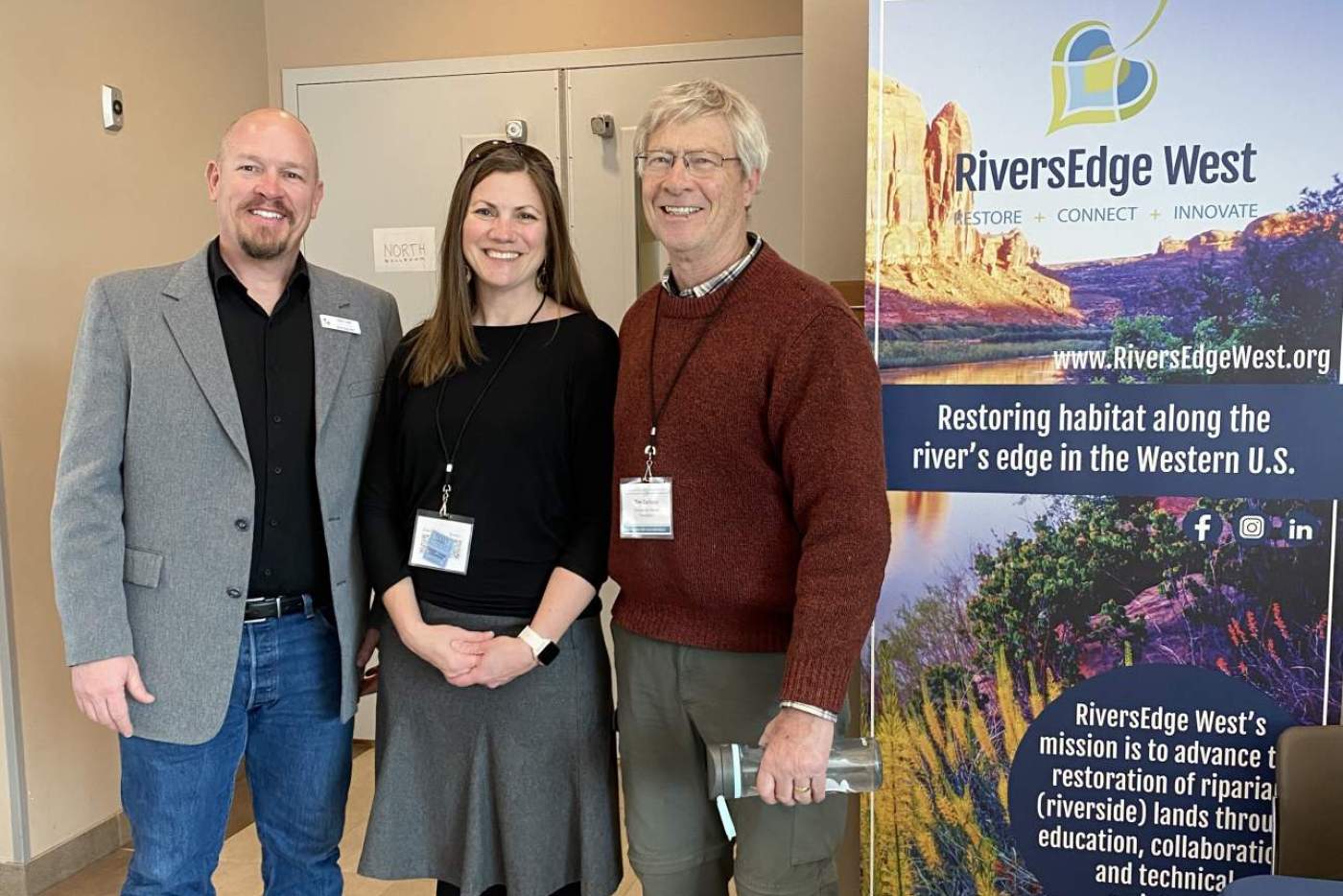 3 conference attendees by RiversEdge West banner